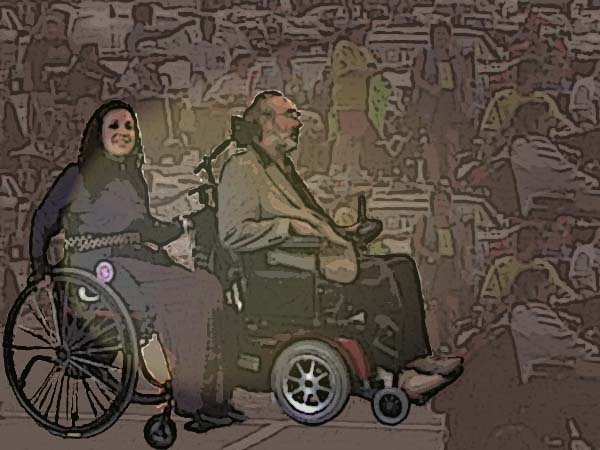Danny in powerchair pulling Nadina in manual chair, crowd in background