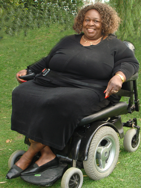 big, smiling woman in black dress, sitting in her powerchair